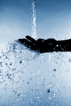 A stream of water pours down from above onto an open hand, ready to receive and ready to give.